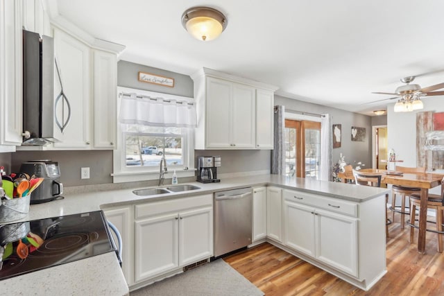 kitchen featuring appliances with stainless steel finishes, sink, white cabinets, kitchen peninsula, and light wood-type flooring