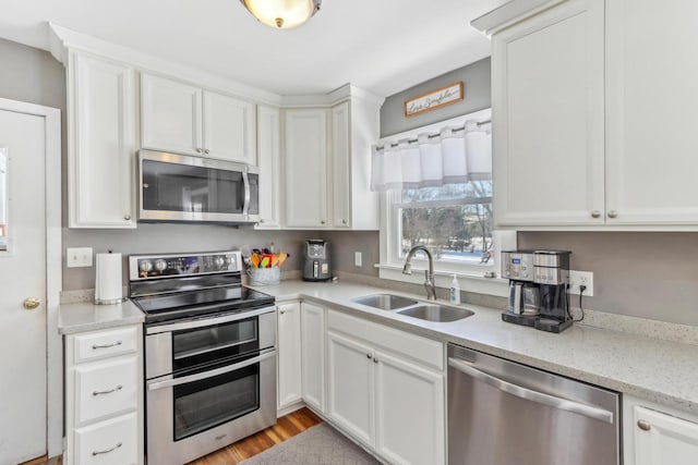 kitchen with light stone countertops, appliances with stainless steel finishes, sink, and white cabinets