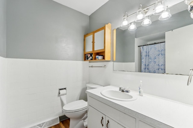 bathroom with tile walls, vanity, and toilet