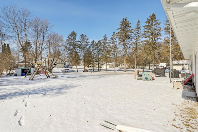 yard covered in snow featuring a playground