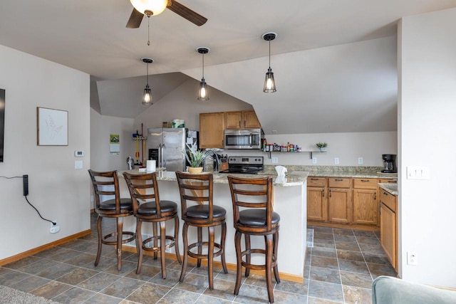 kitchen featuring hanging light fixtures, a kitchen bar, stainless steel appliances, and light stone counters