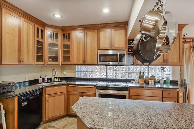 kitchen with hanging light fixtures, appliances with stainless steel finishes, sink, and dark stone counters