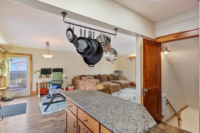 kitchen featuring light stone counters, hanging light fixtures, and light wood-type flooring