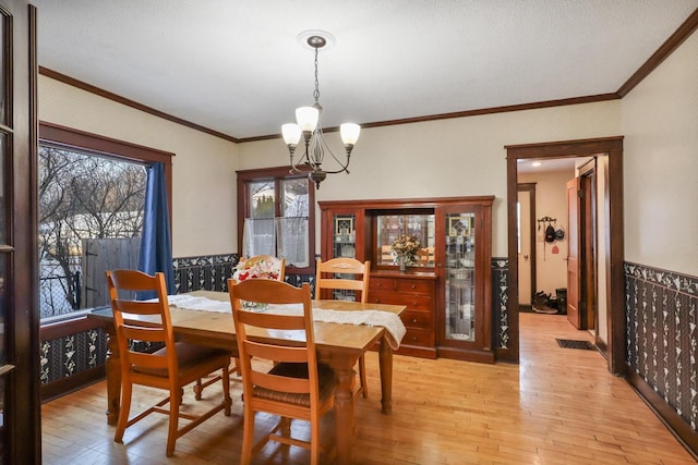 dining space featuring an inviting chandelier, crown molding, and light wood-type flooring