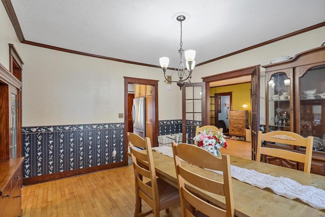 dining room with a notable chandelier, crown molding, light hardwood / wood-style floors, and a textured ceiling