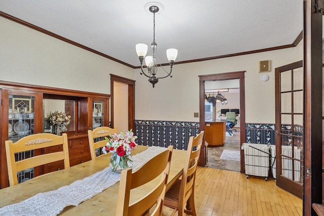 dining area with crown molding, light wood-type flooring, and a chandelier