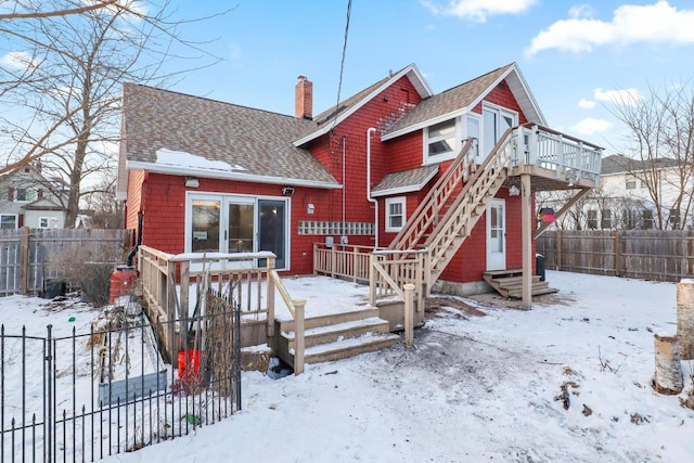 snow covered rear of property with a wooden deck