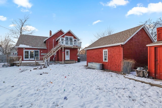 snow covered back of property with a deck