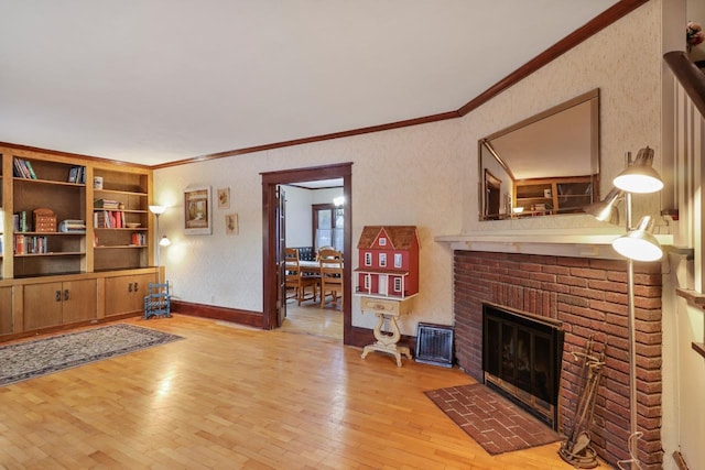 living room featuring crown molding, a fireplace, and light hardwood / wood-style floors