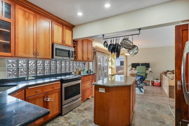 kitchen featuring stainless steel appliances, a center island, sink, and dark stone countertops