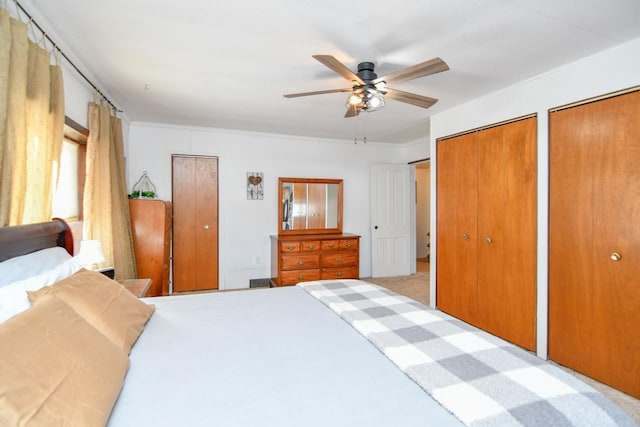 carpeted bedroom featuring multiple closets and ceiling fan