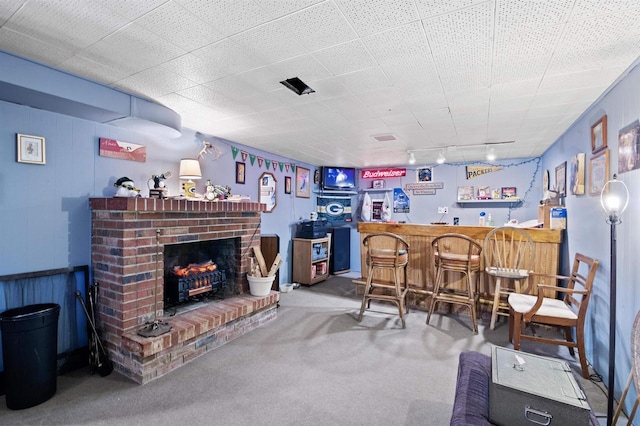 bar with rail lighting, a brick fireplace, and carpet