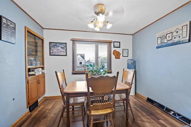 dining area featuring an inviting chandelier, ornamental molding, and dark hardwood / wood-style floors