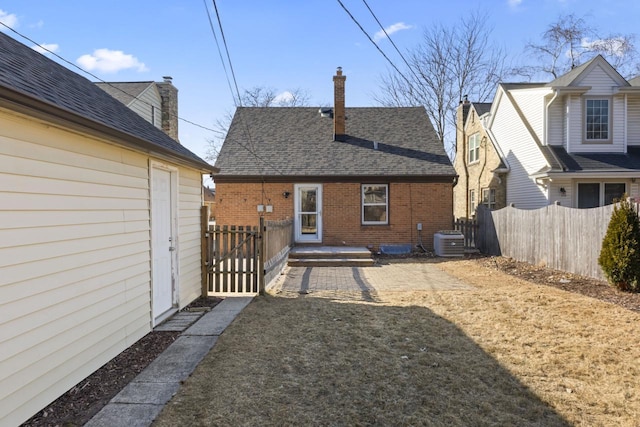 rear view of property featuring central AC unit and a lawn