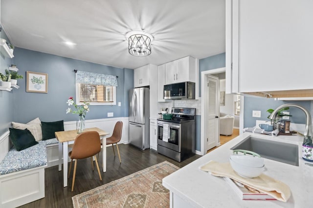 kitchen featuring sink, dark wood-type flooring, appliances with stainless steel finishes, white cabinetry, and breakfast area