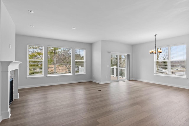 unfurnished living room featuring a notable chandelier, hardwood / wood-style floors, and a wealth of natural light