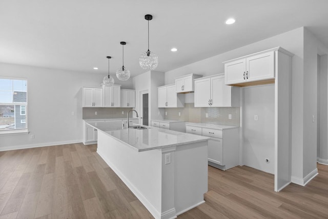 kitchen with a kitchen island with sink and white cabinets