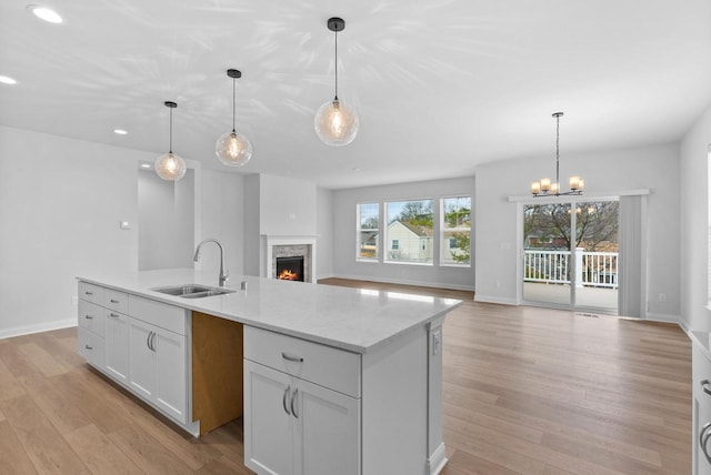 kitchen featuring sink, a center island, white cabinets, decorative light fixtures, and light wood-type flooring