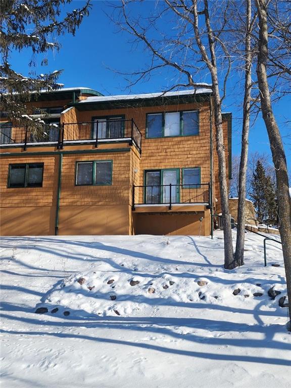 snow covered back of property with a balcony