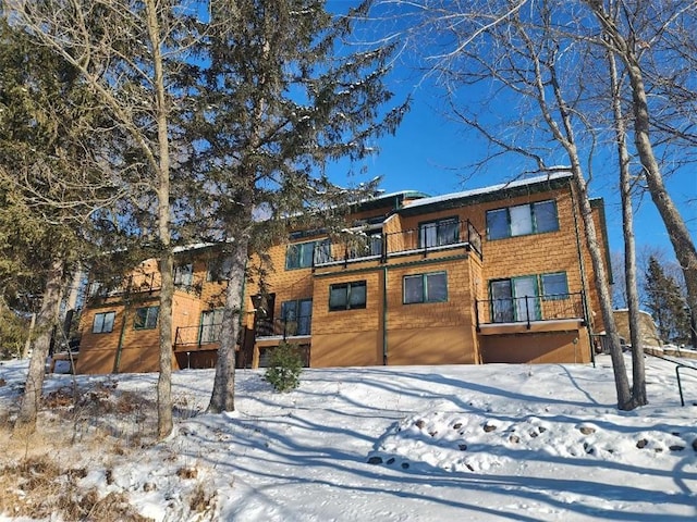 snow covered back of property with a balcony