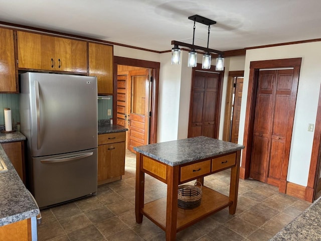 kitchen featuring pendant lighting, crown molding, and stainless steel refrigerator