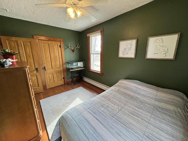 bedroom featuring ceiling fan, hardwood / wood-style flooring, a textured ceiling, and baseboard heating