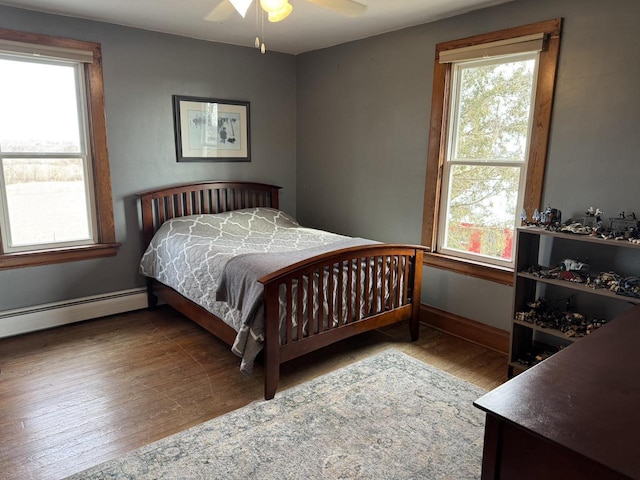 bedroom featuring wood-type flooring, a baseboard heating unit, and ceiling fan