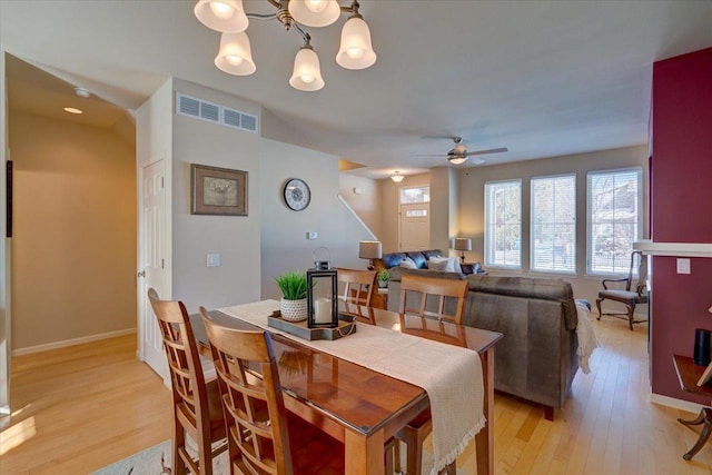 dining area with ceiling fan with notable chandelier and light hardwood / wood-style floors