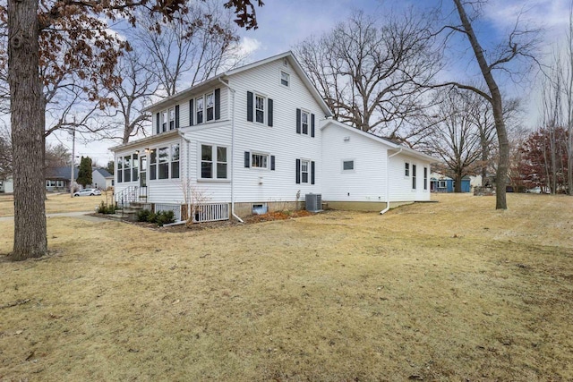 back of house featuring a sunroom, central AC, and a lawn