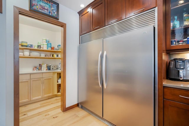 kitchen featuring stainless steel built in refrigerator and light hardwood / wood-style flooring