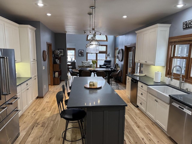 kitchen with stainless steel appliances, dark countertops, a sink, and white cabinetry