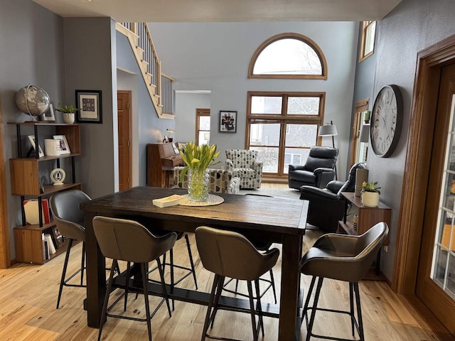 dining space with light wood finished floors and stairway