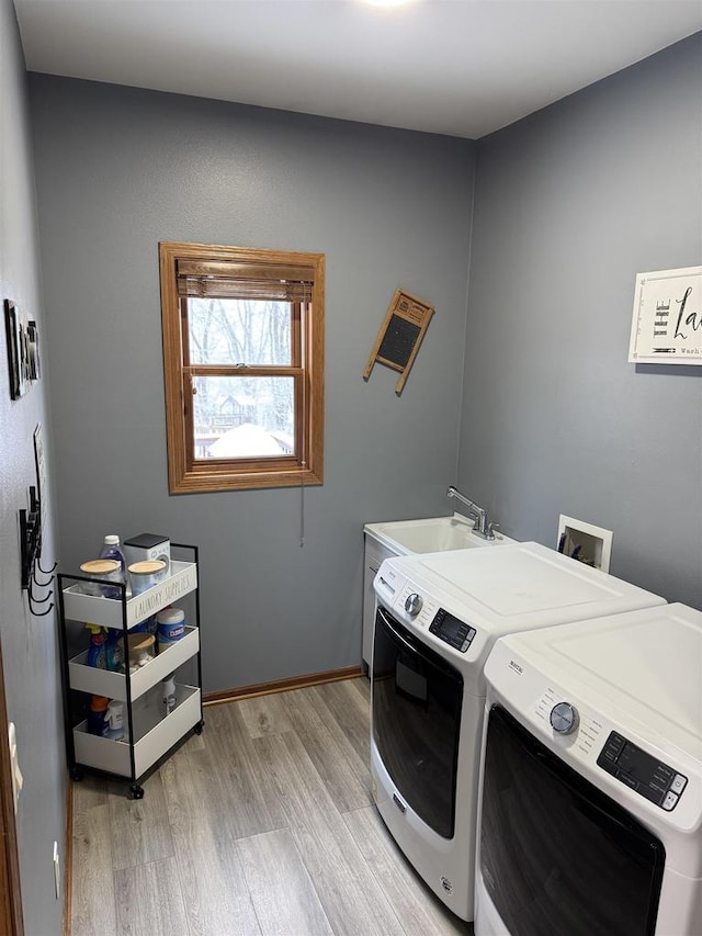 laundry area featuring light wood-style floors, independent washer and dryer, laundry area, and a sink