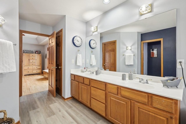 full bath with double vanity, wood finished floors, and a sink