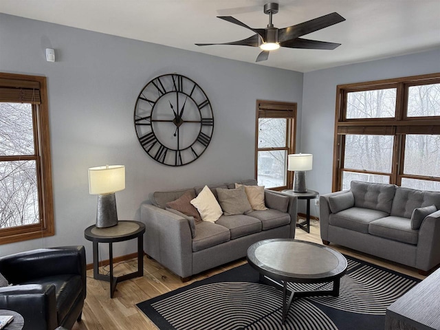 living area with plenty of natural light, light wood-style flooring, baseboards, and a ceiling fan