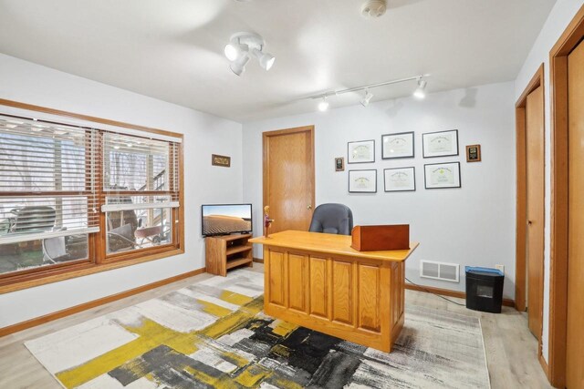 office space featuring light wood-style floors, baseboards, visible vents, and rail lighting