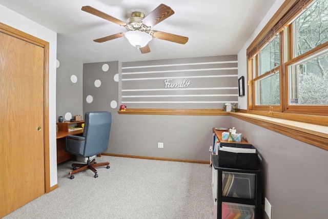 carpeted office space featuring a ceiling fan and baseboards