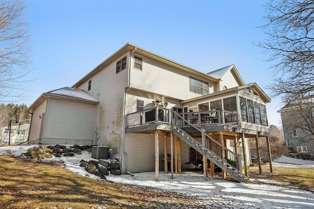 snow covered house featuring a sunroom, central AC, and stairway