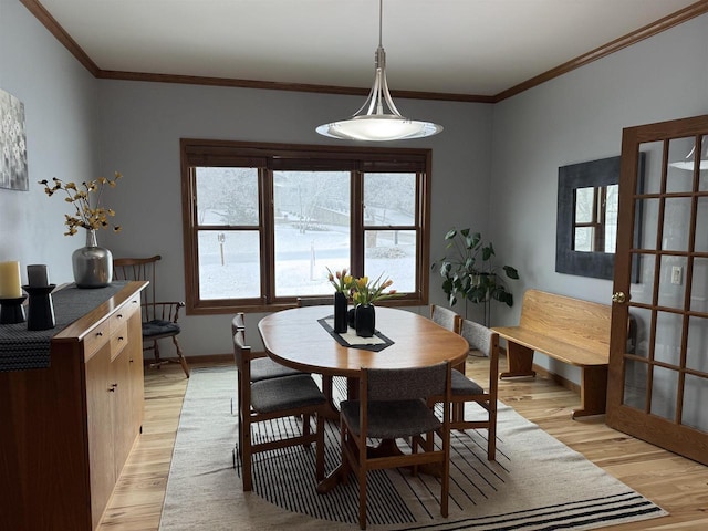 dining room featuring baseboards, ornamental molding, and light wood-style floors