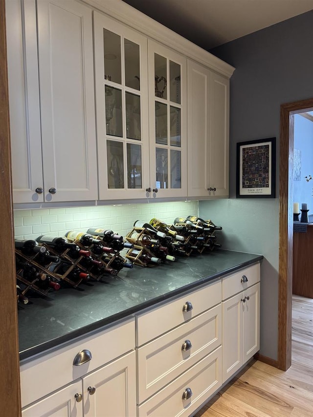 bar featuring backsplash and light wood finished floors