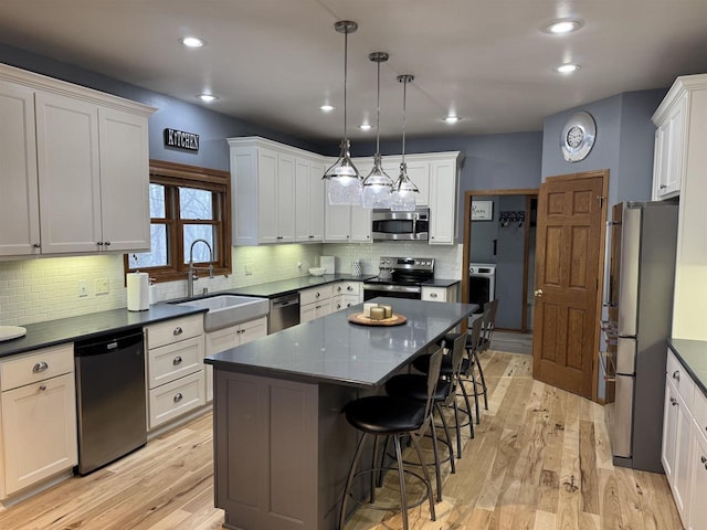 kitchen with appliances with stainless steel finishes, a kitchen breakfast bar, a sink, and light wood finished floors