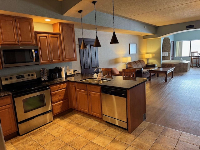 kitchen featuring appliances with stainless steel finishes, pendant lighting, sink, light tile patterned floors, and kitchen peninsula