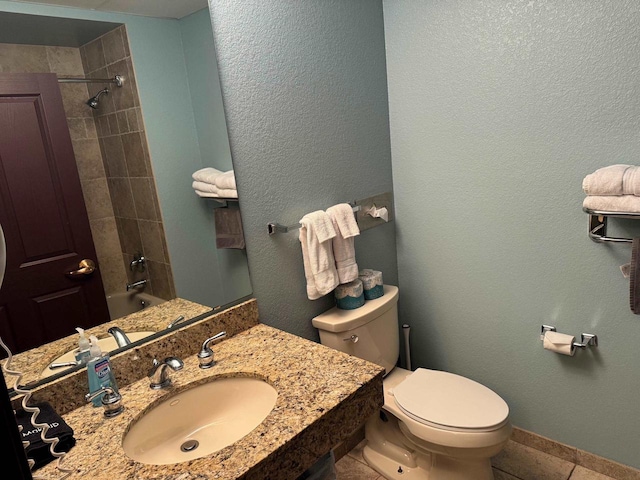 full bathroom featuring tile patterned floors, toilet, tiled shower / bath combo, and sink