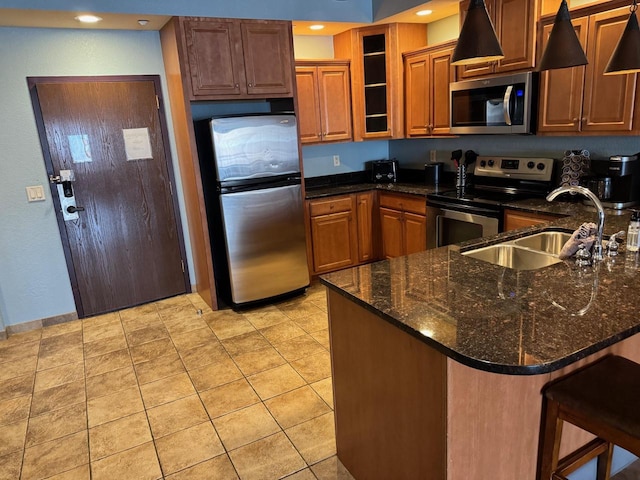 kitchen with sink, light tile patterned floors, dark stone counters, kitchen peninsula, and stainless steel appliances