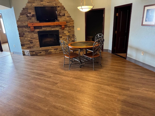 dining space with a stone fireplace and hardwood / wood-style flooring