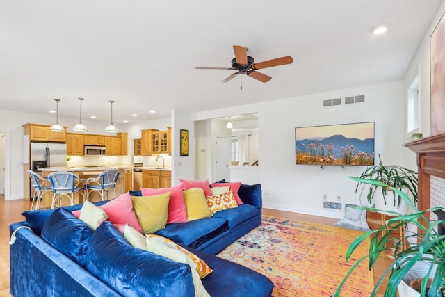 living room featuring sink, light hardwood / wood-style flooring, and ceiling fan