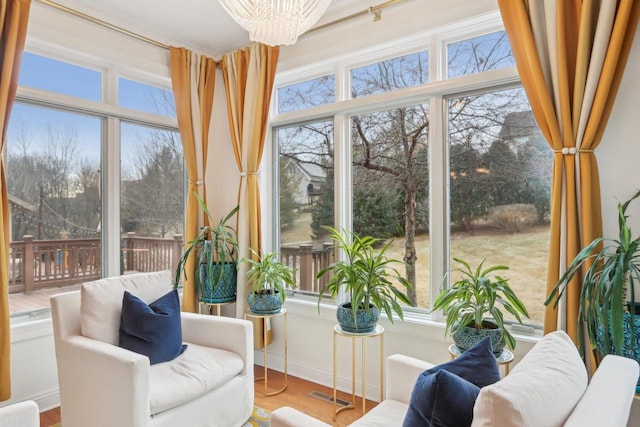 sunroom / solarium featuring a healthy amount of sunlight and a chandelier