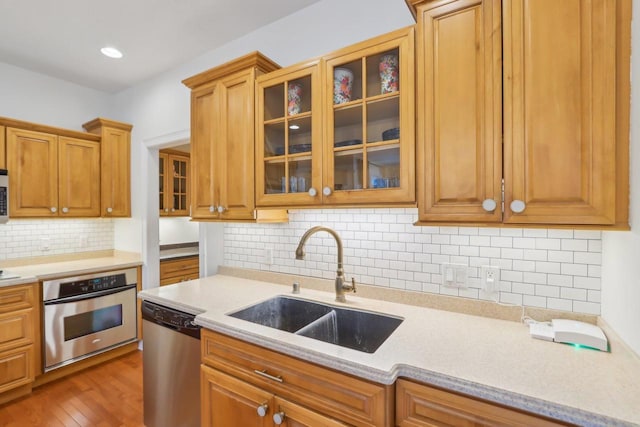 kitchen with sink, backsplash, hardwood / wood-style floors, and appliances with stainless steel finishes