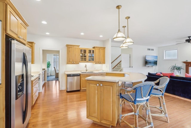 kitchen with appliances with stainless steel finishes, a breakfast bar, decorative light fixtures, sink, and a center island