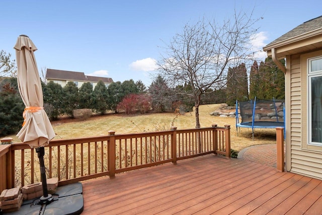 wooden terrace featuring a trampoline and a yard